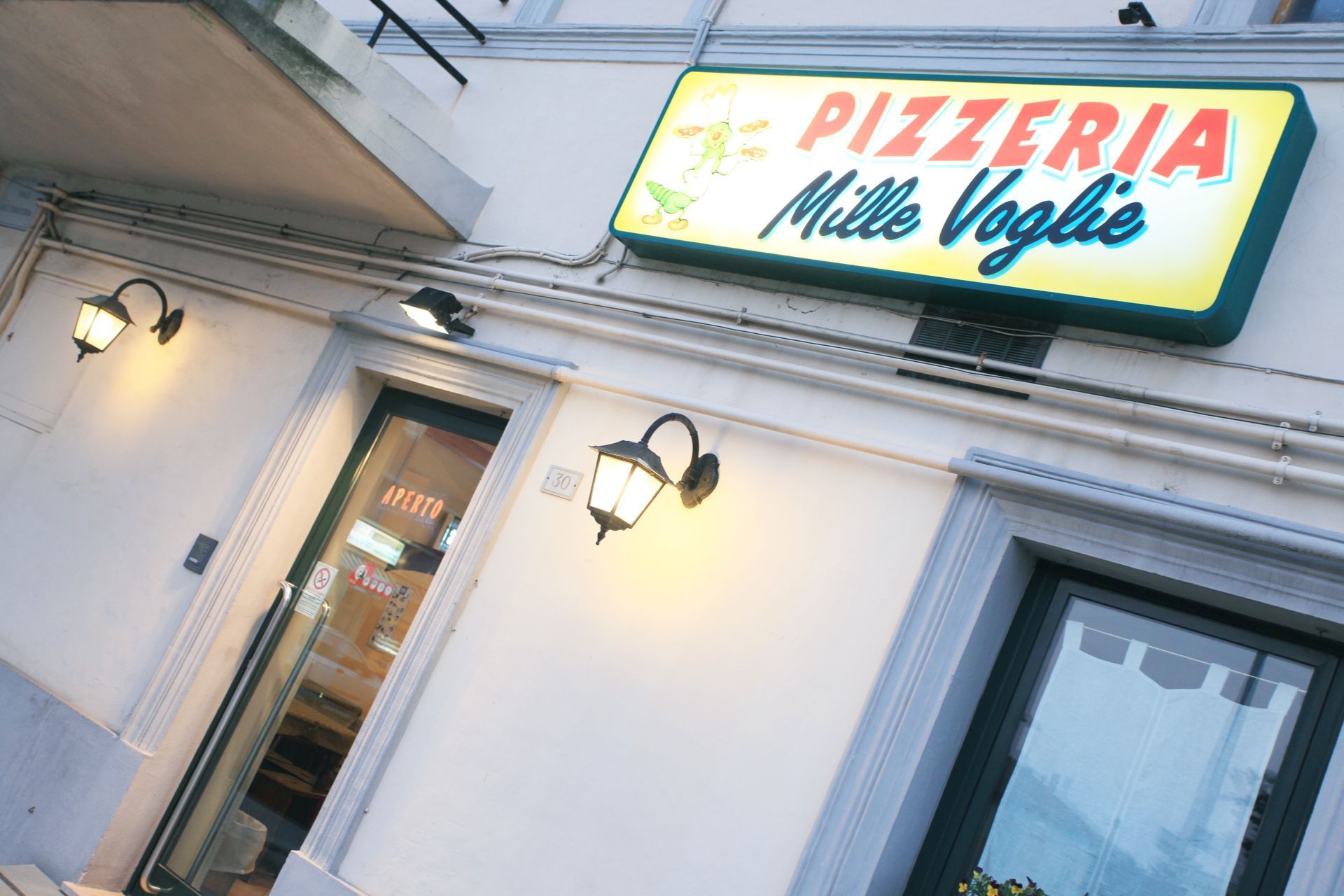 Insegna di pizzeria sopra una vetrina bianca con applique e finestre