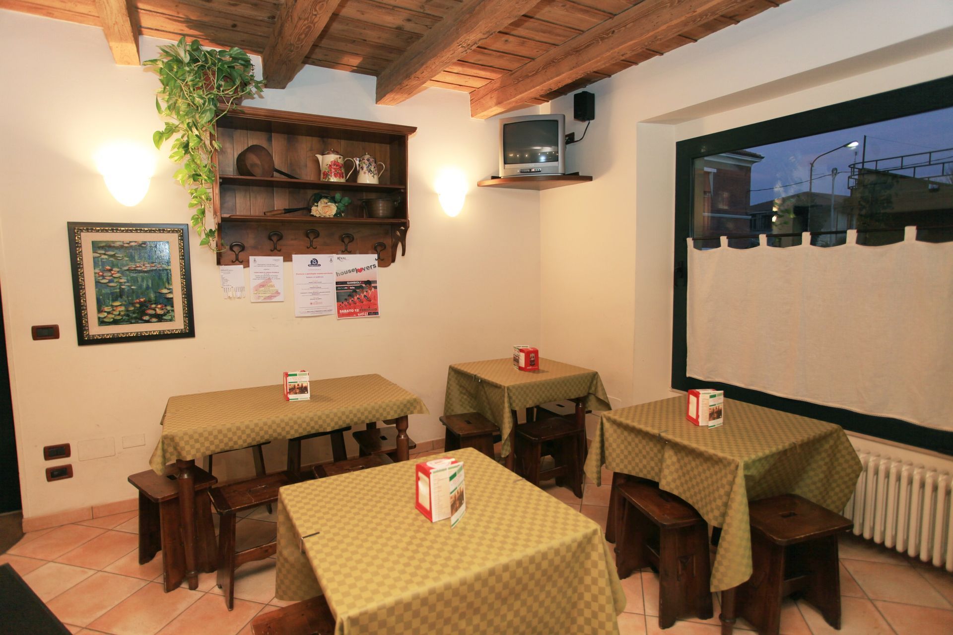 Ristorante-bar in stile rustico con pavimento piastrellato, travi in legno e illuminazione calda.