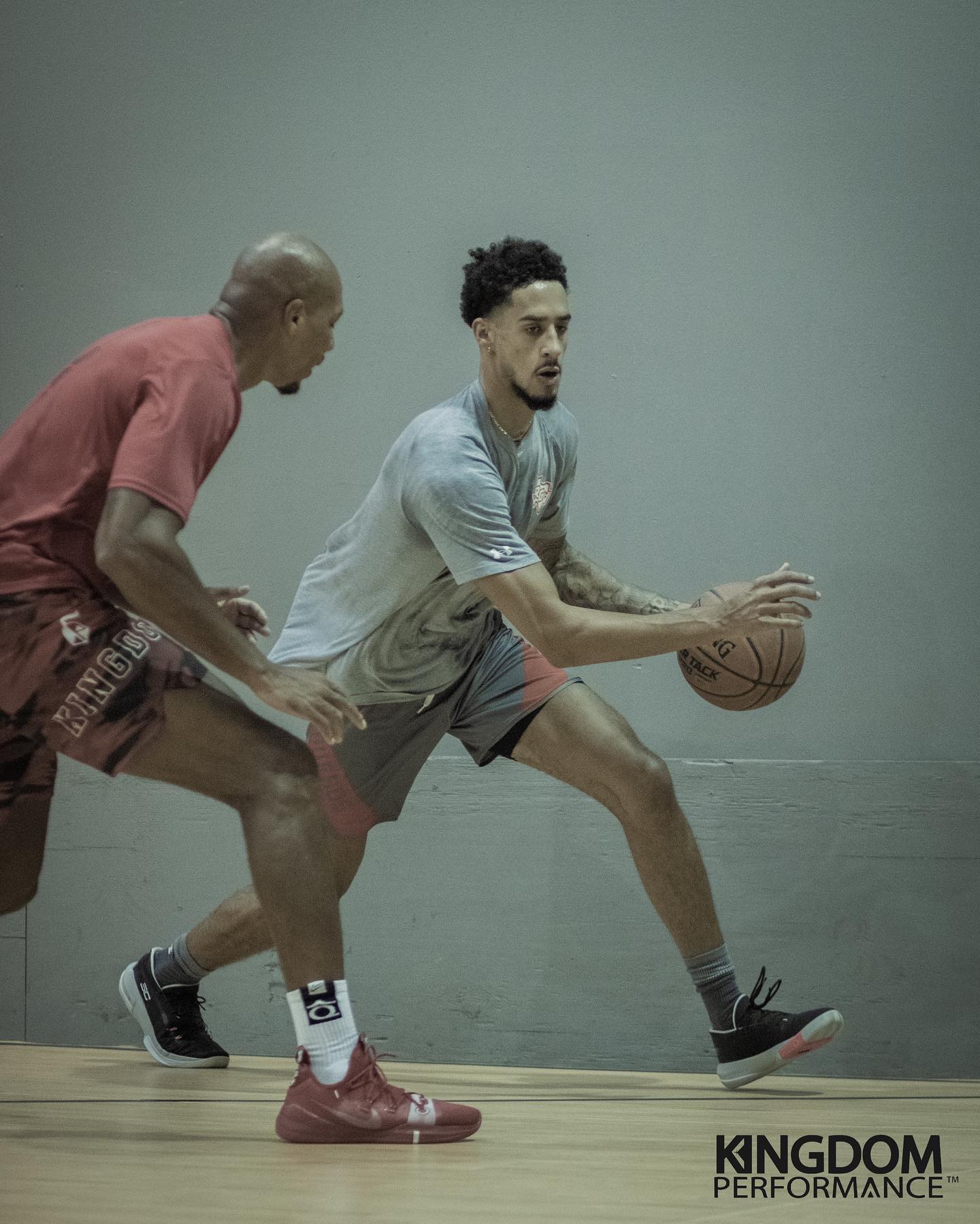 A basketball player dribbles the ball while being guarded in a training session.