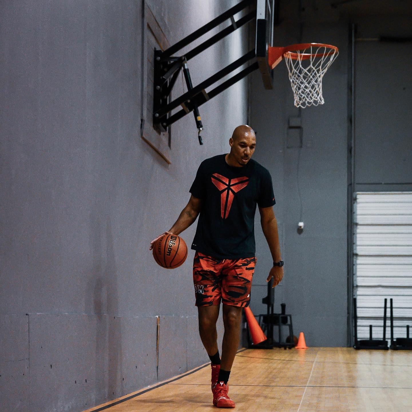 Man in Kobe Bryant shirt dribbles basketball on court.
