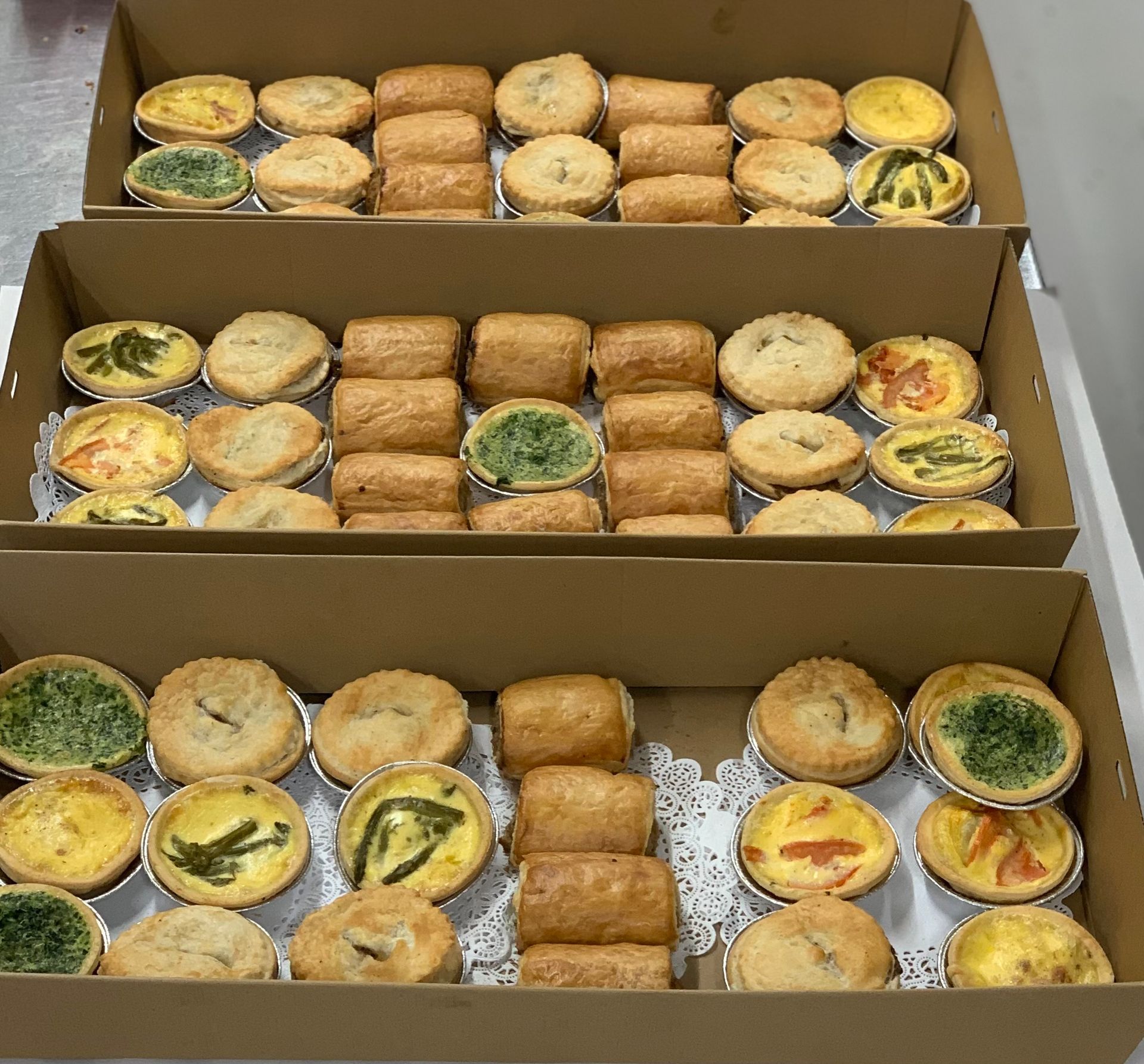Three boxes filled with assorted savory pastries: quiches, rolls, and tarts— Bread Basket in Kurri Kurri, NSW