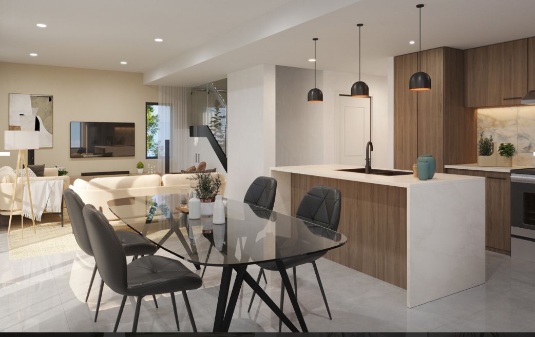Modern open-plan kitchen and dining area with white chairs, black table, wood cabinetry, and pendant lights.