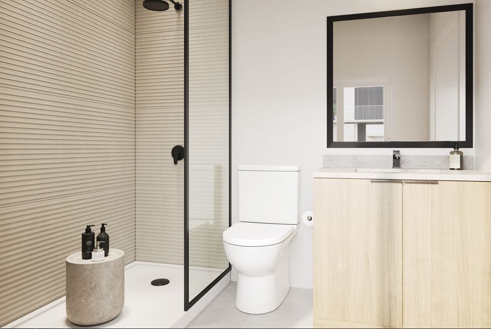 Modern bathroom with glass shower, toilet, sink vanity, and round stool with bottles