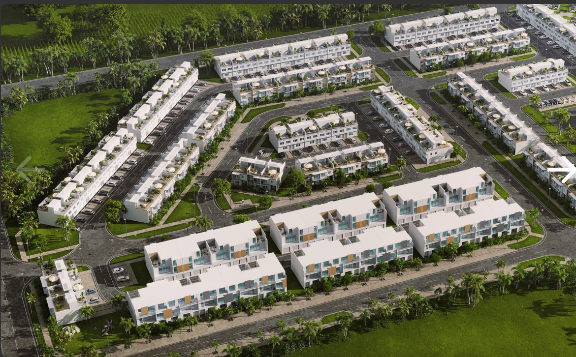 Aerial view of a modern apartment complex with white buildings, roads, and green landscaping
