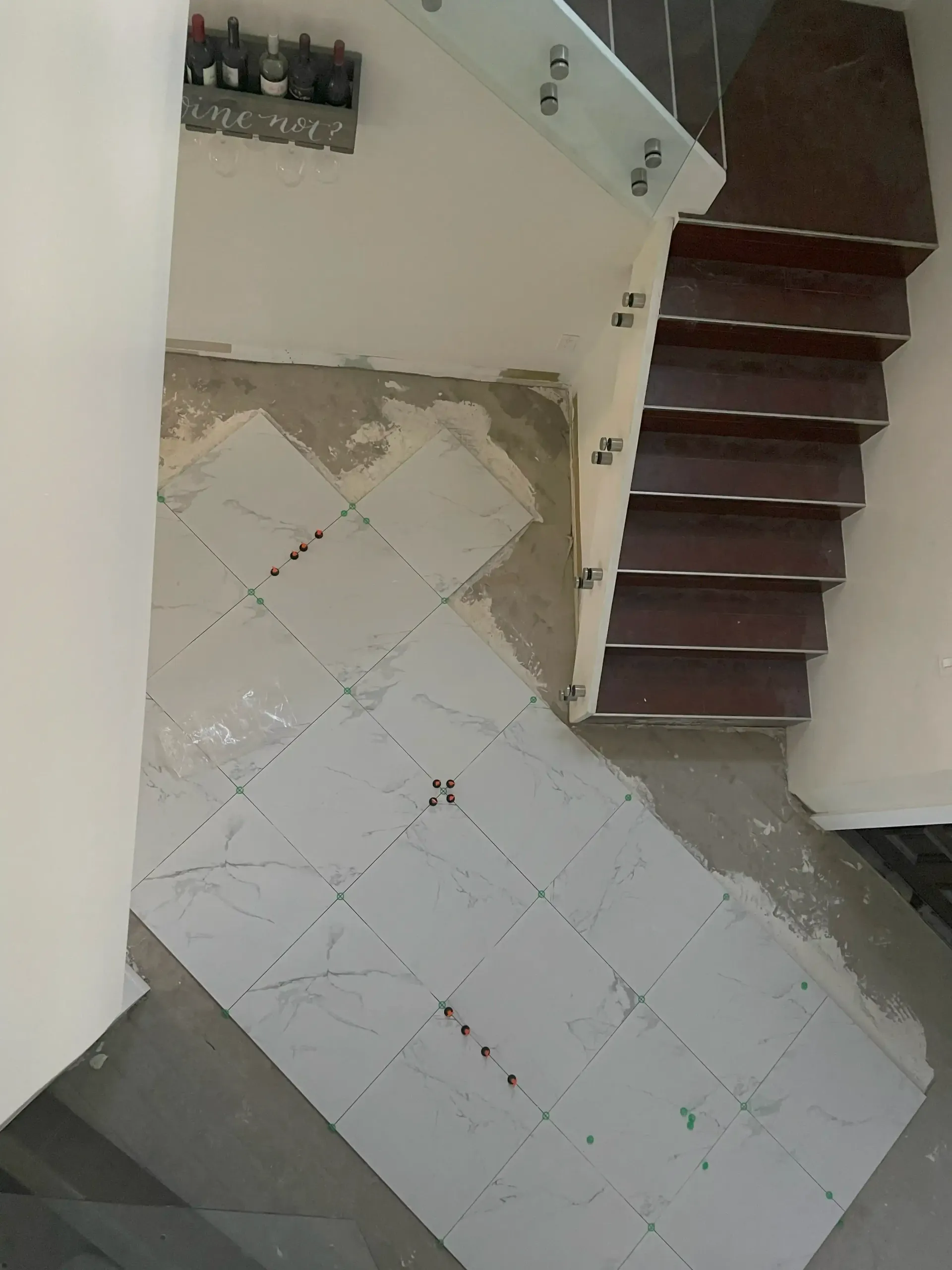 Indoor stairwell with white tiled floor and a dark wooden staircase on the right.