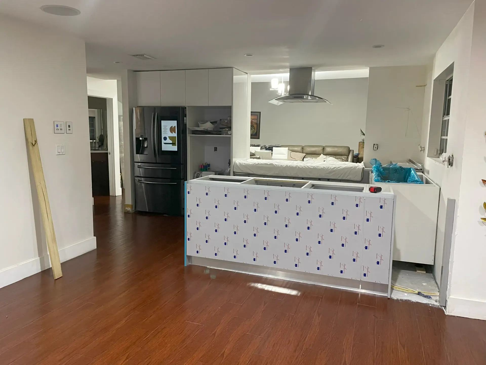 Open-plan kitchen and living area with hardwood floors, gray cabinets, and a patterned kitchen island cover.