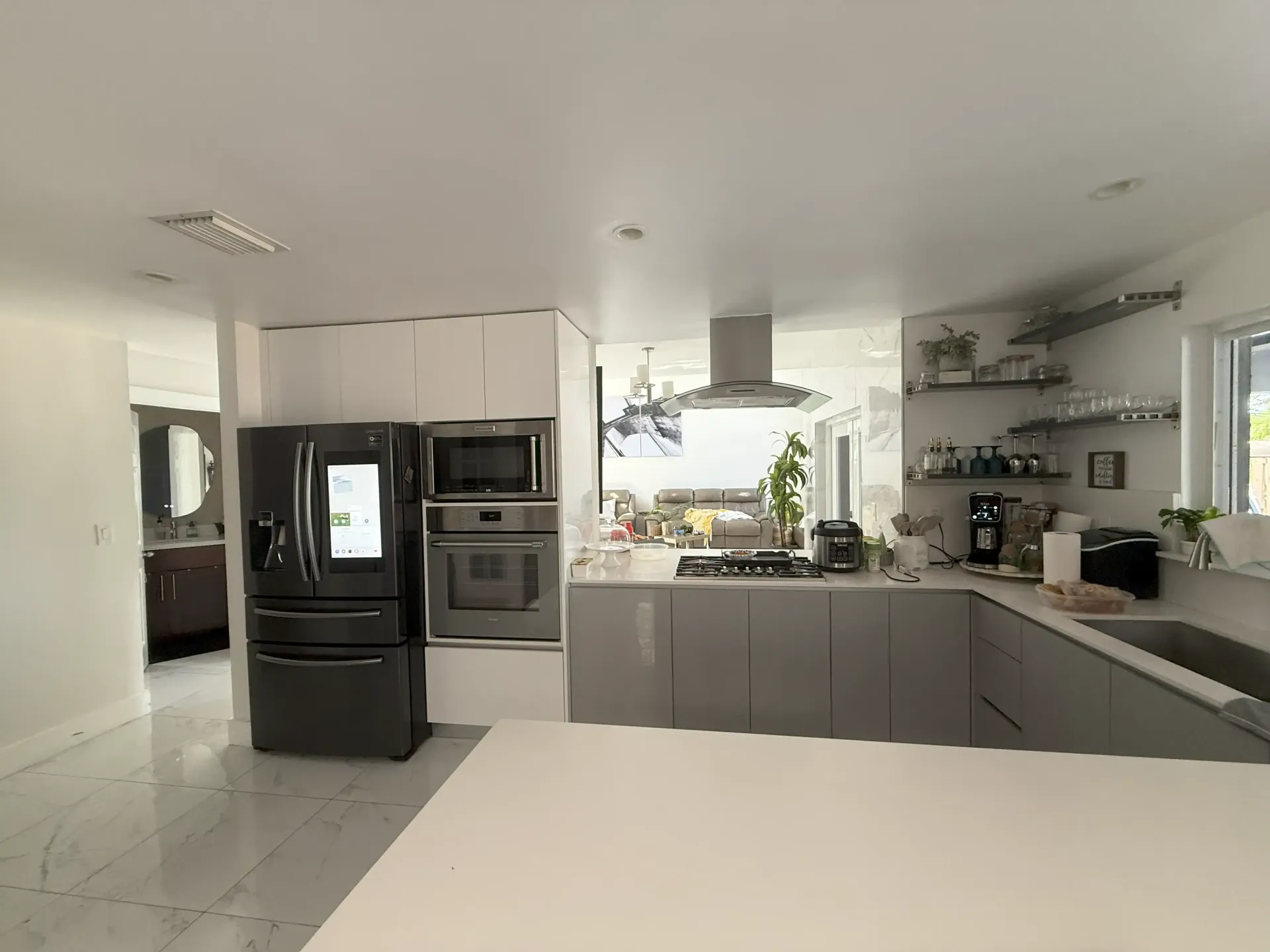 Modern kitchen with gray cabinets, black appliances, white countertops, and a bright open layout.