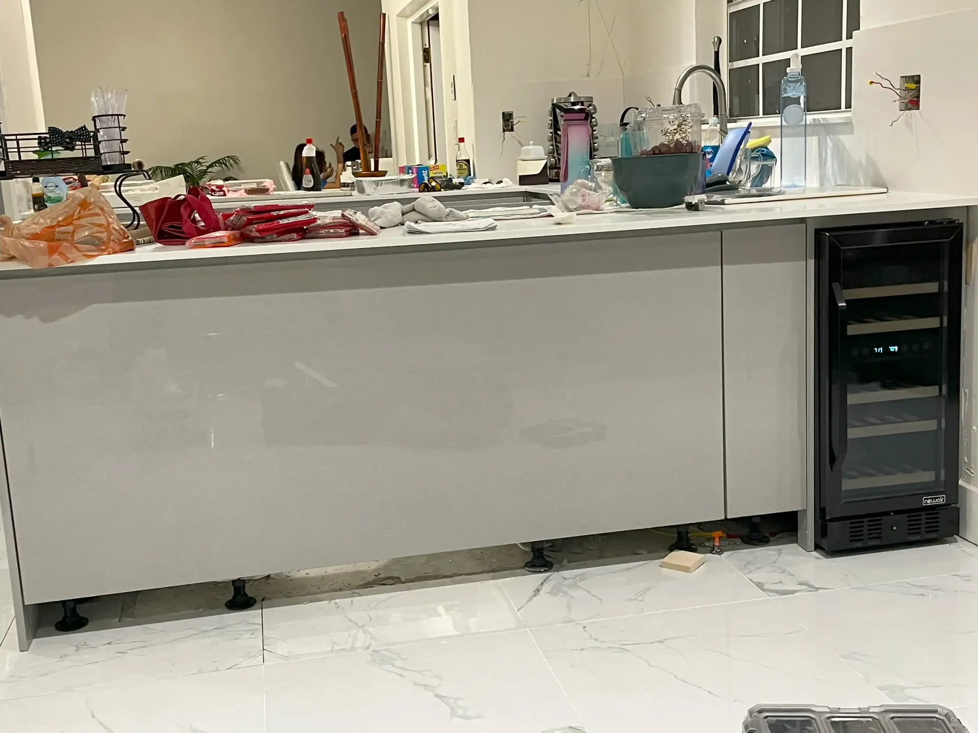Kitchen island with scattered items and a black cabinet on the right in a bright room