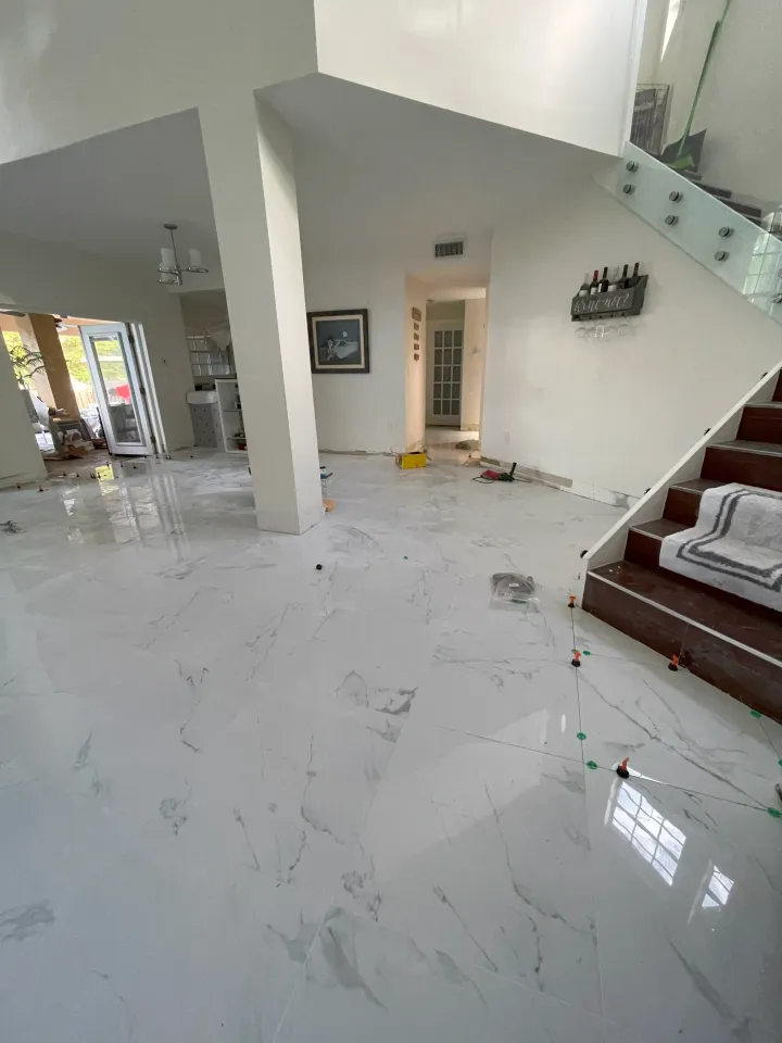 Bright modern living room with glossy white marble floor, stairs, and white columns