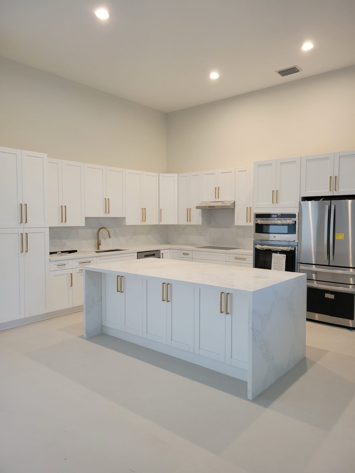 Bright modern kitchen with white cabinets, marble island, stainless steel appliances, and recessed lighting