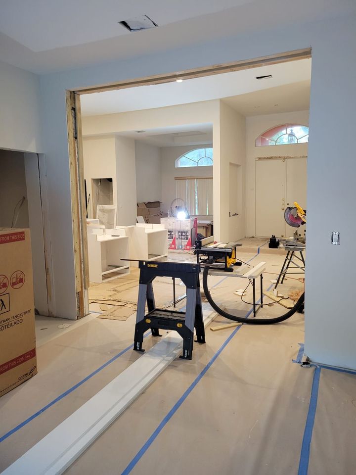 Home renovation with open wall framing, tools, and taped floor in a doorway between rooms