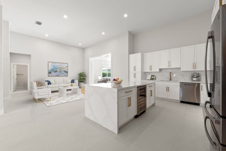 Bright open-concept kitchen and living room with white cabinets, island, and light gray decor