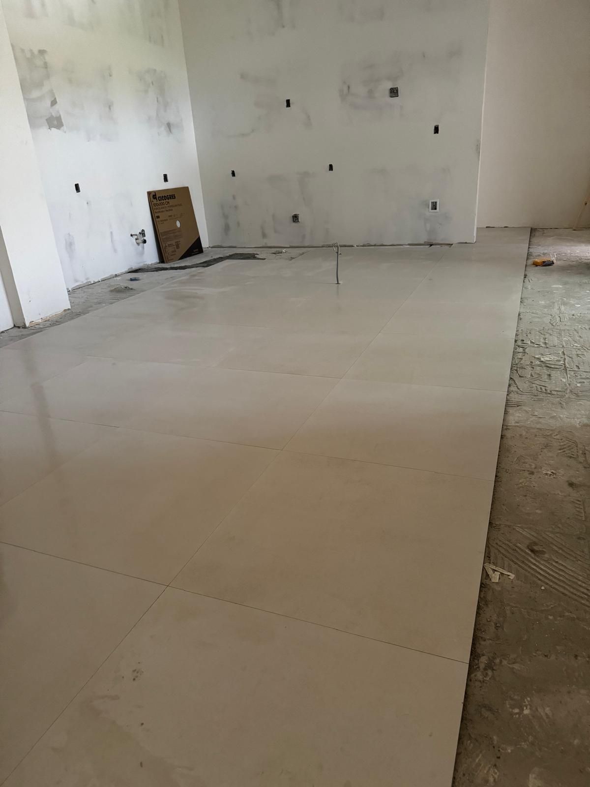 Bare unfinished room with concrete floor, white walls, and construction debris in the corner