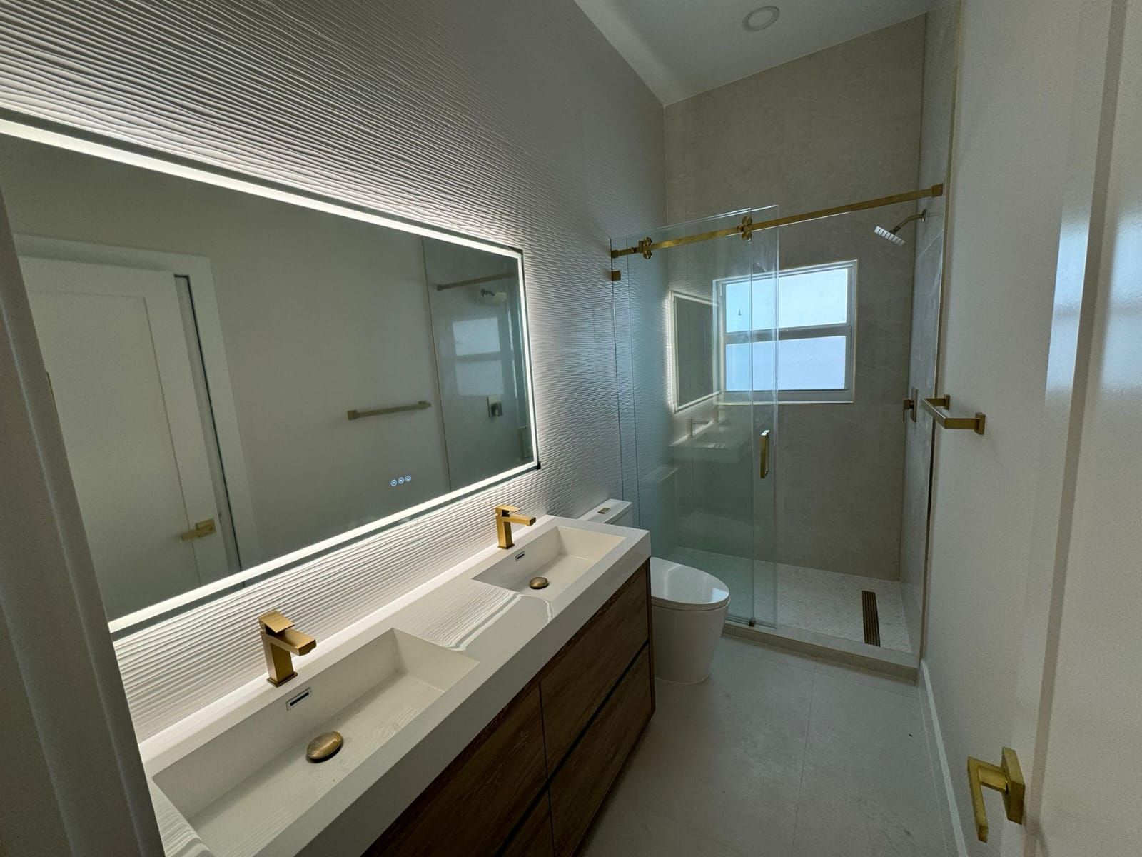 Modern bathroom with double vanity, large mirror, and glass-enclosed shower.