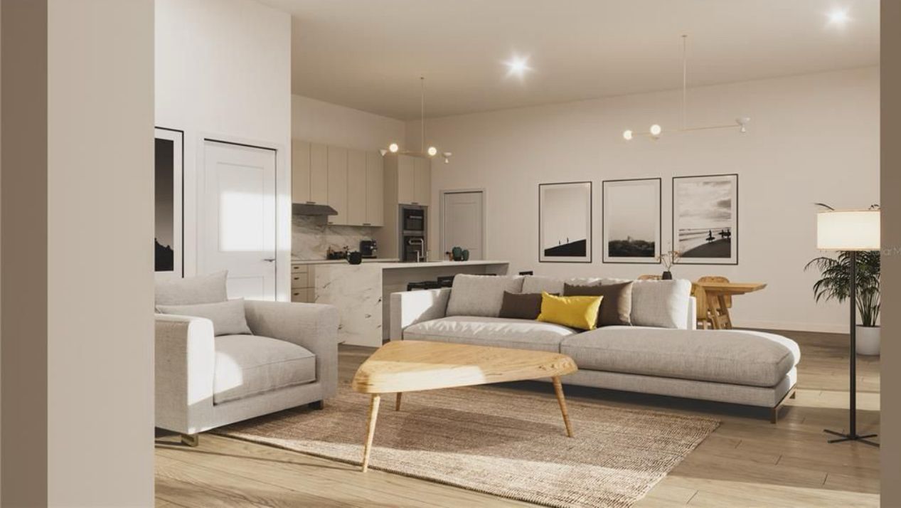 Modern beige living room with sofa, armchair, coffee table, and open kitchen in the background