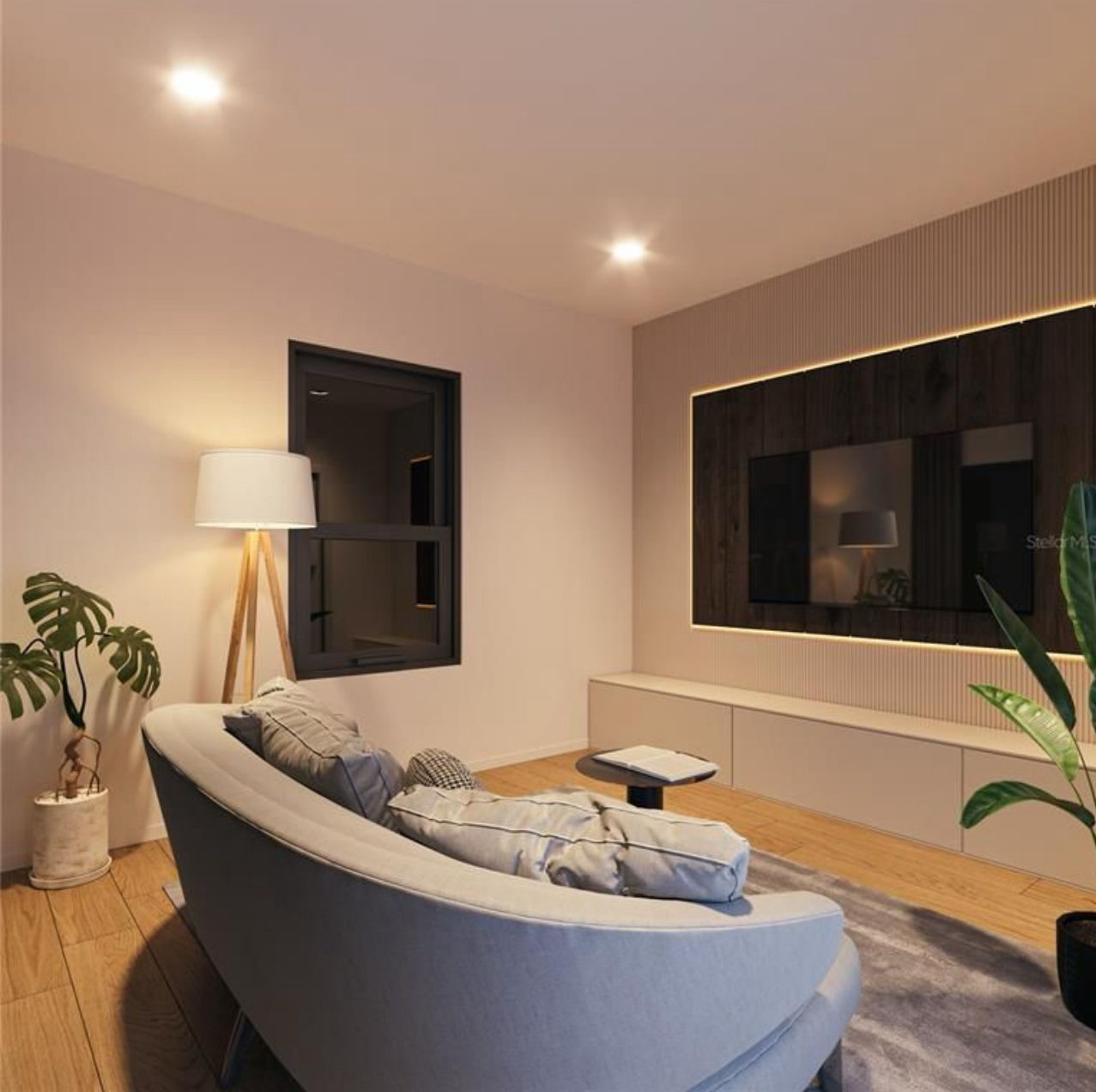 Modern living room with curved gray sofa, floor lamp, plants, and a large wall-mounted TV.