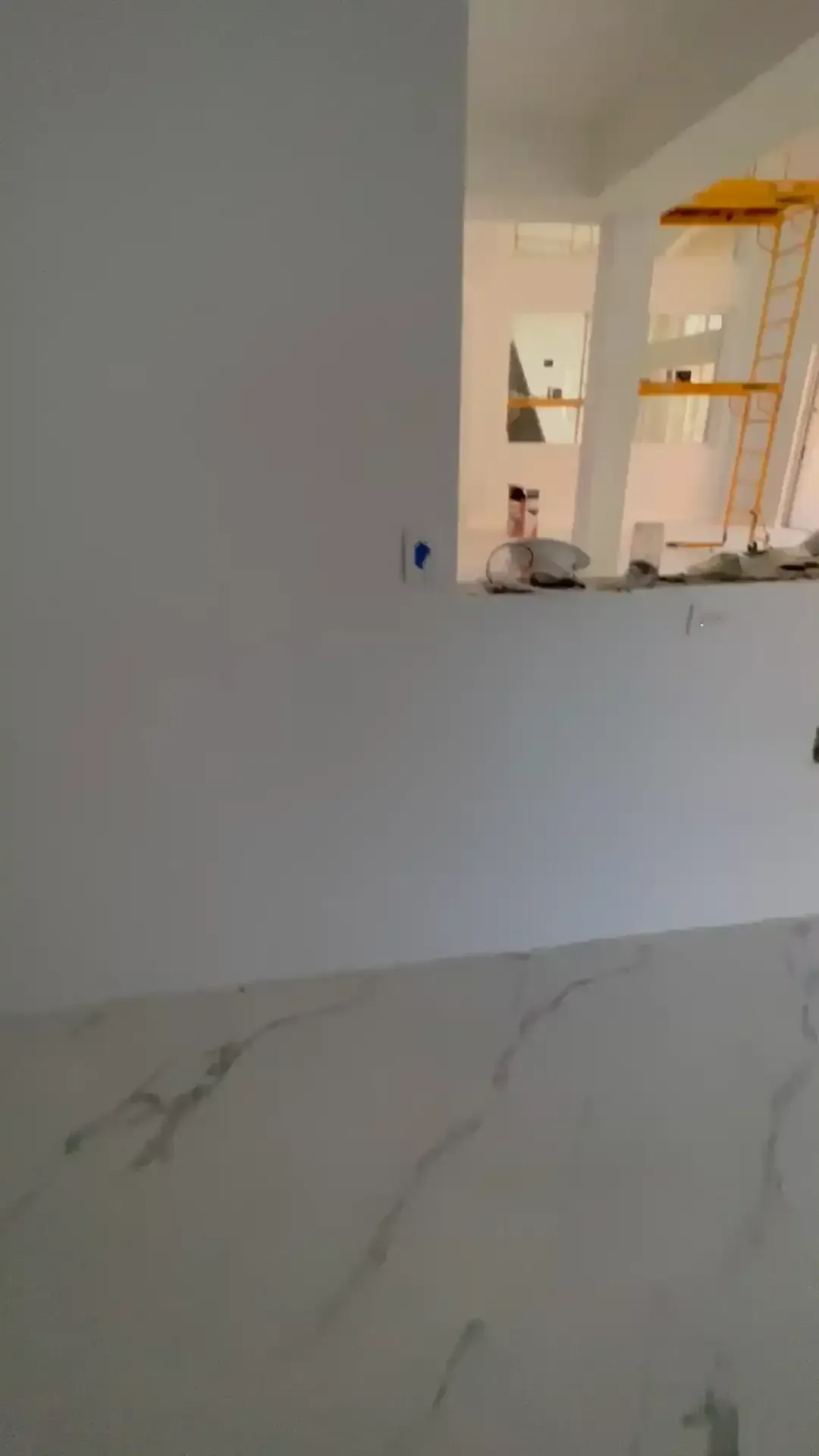 Empty white room with marble floor and a kitchen pass-through window on the right