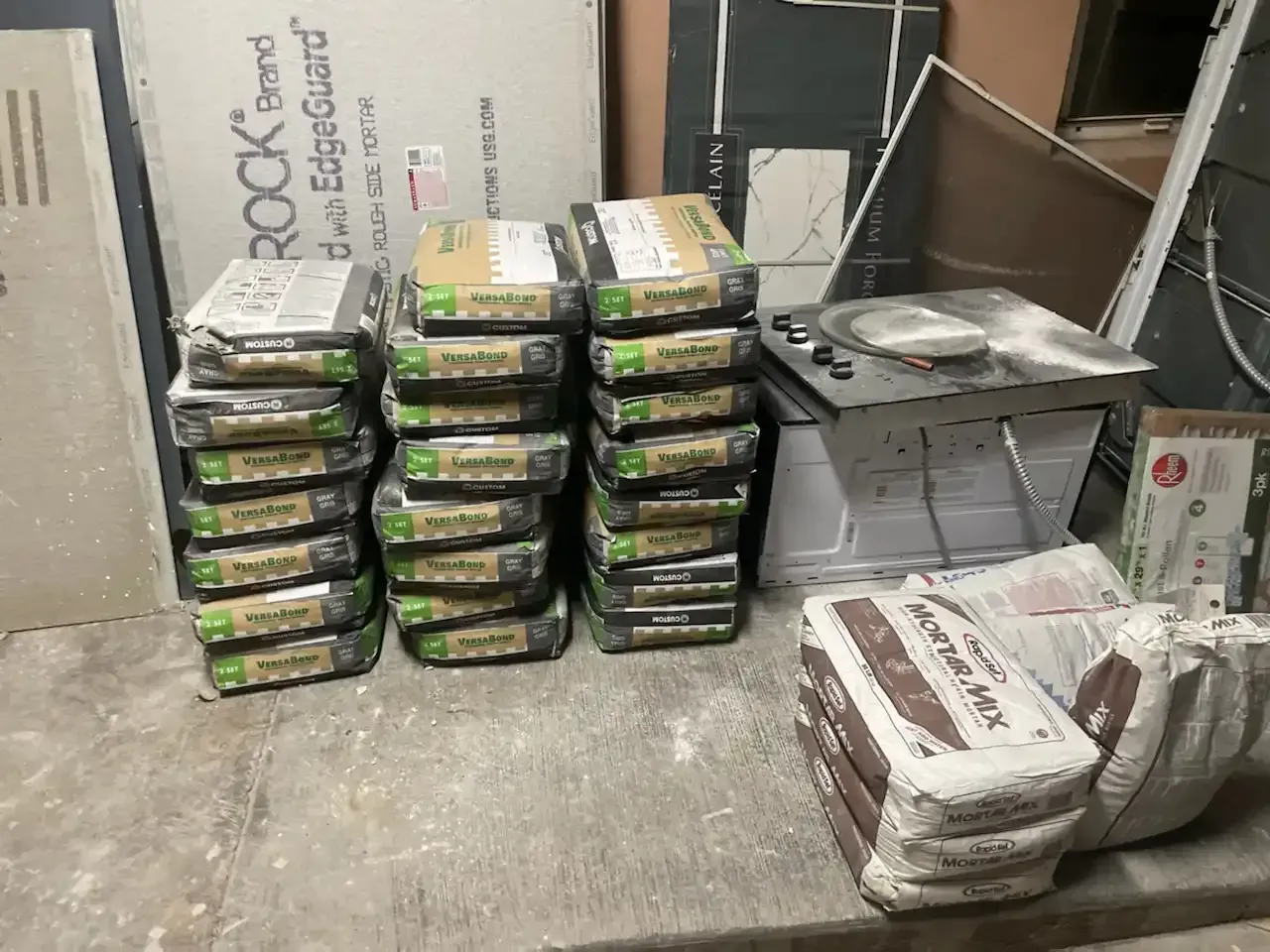 Stacked packaged food trays and bags in a storage area, with cardboard boxes and shelving nearby.