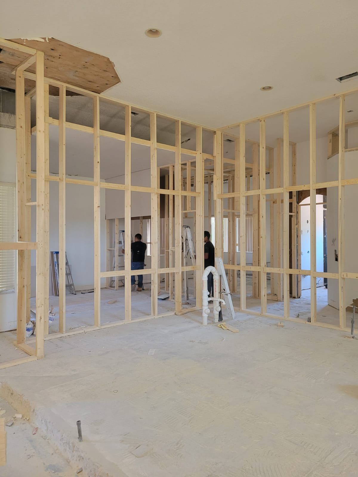 Interior under construction with exposed wood framing and a ladder on a dusty floor