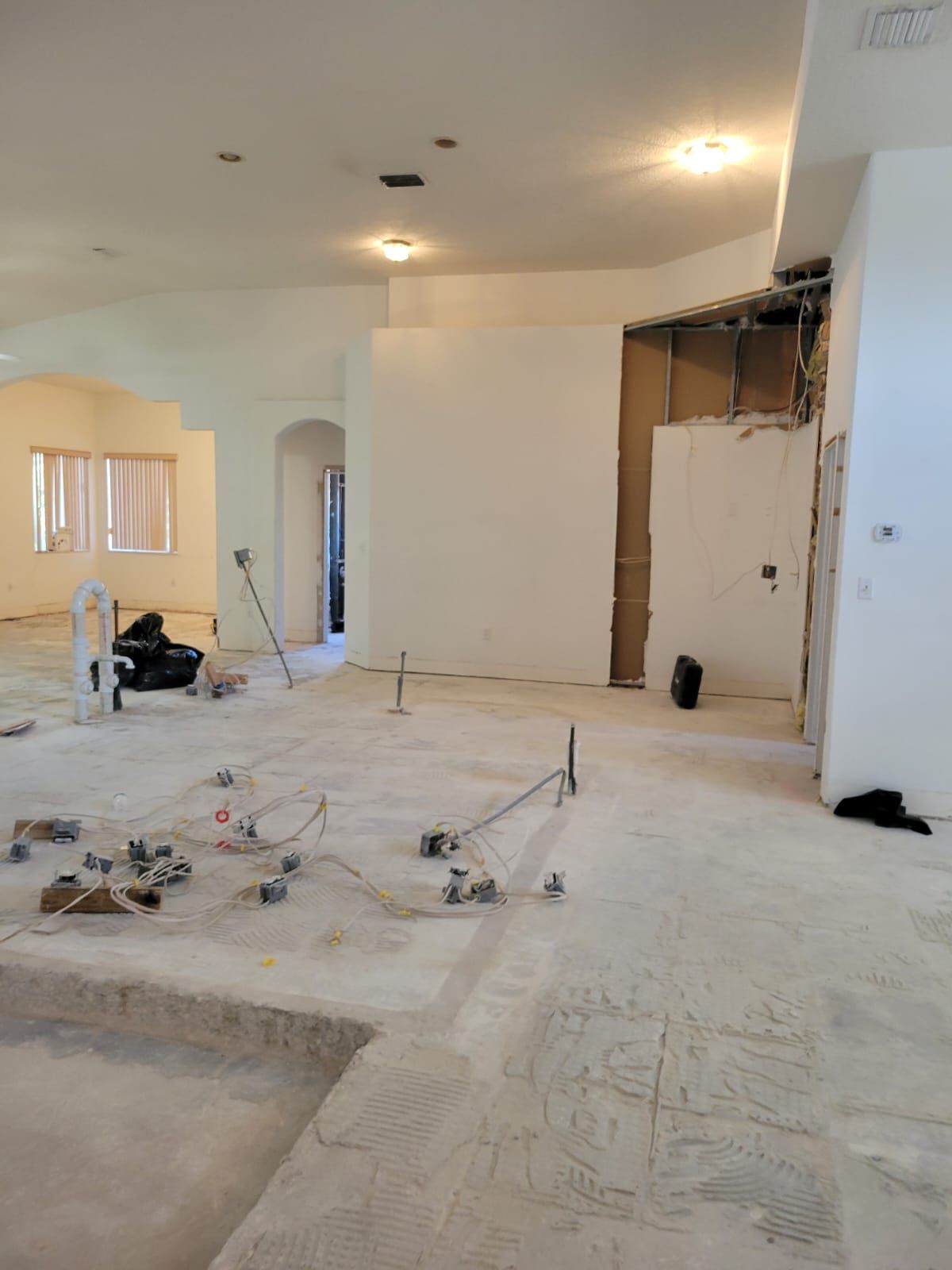Renovated living room with unfinished walls, exposed wiring, and construction debris on the floor
