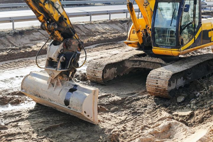 Yellow excavator with bucket on a muddy construction site