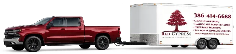 Red pickup truck towing a white trailer. The trailer has a tree logo and a phone number.