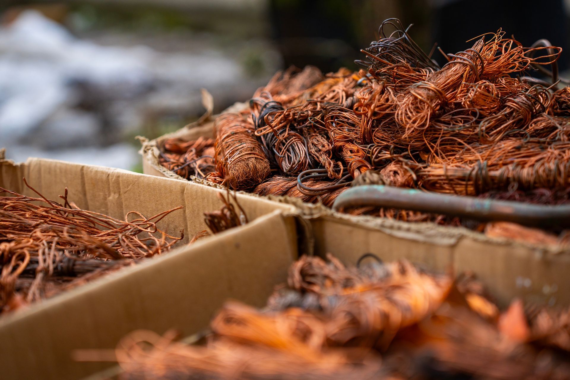 Cardboard boxes filled with tangled copper wire scrap, highlighting metal recycling.