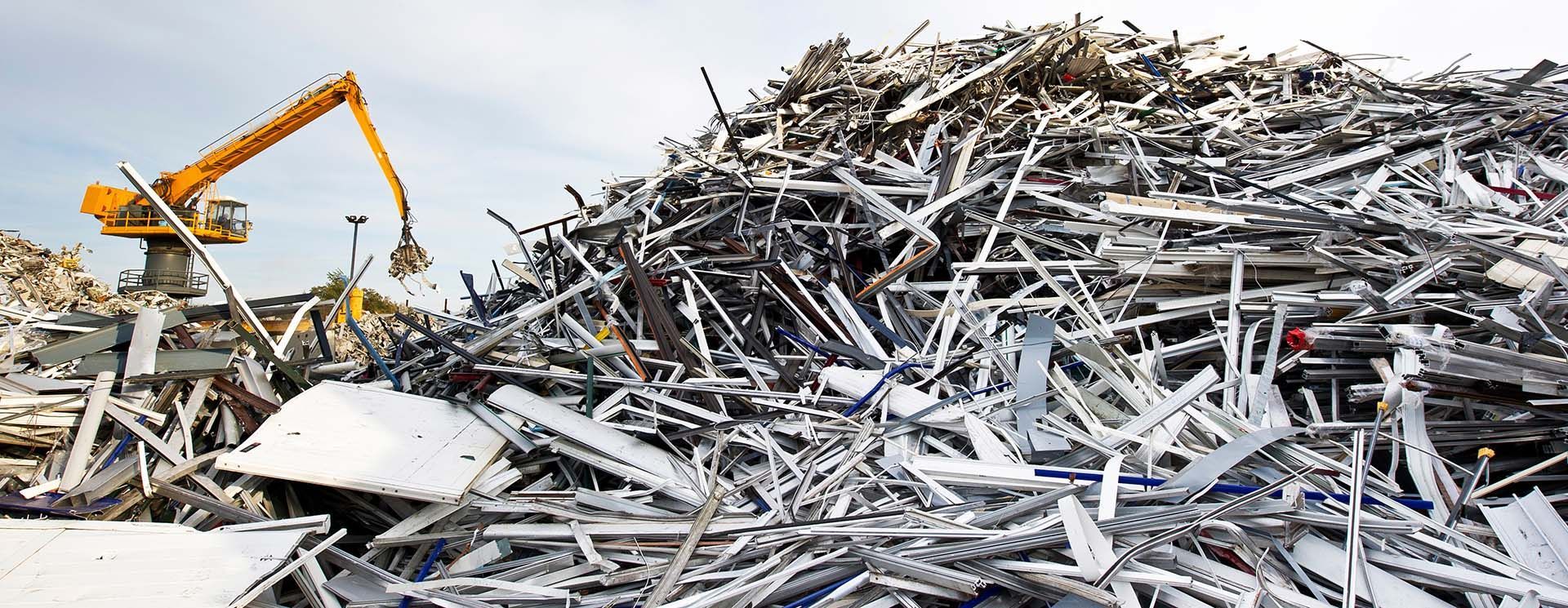 Large stack of aluminum and ferrous materials scrap with yellow crane in the background. Large stack of aluminum and ferrous materials scrap with yellow crane in the background.
