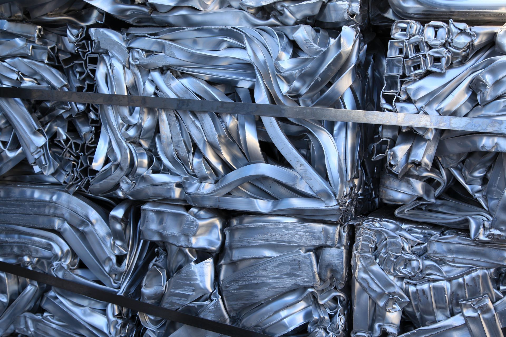 Compressed bundles of shiny aluminum scrap metal tightly packed and strapped, ready for recycling.