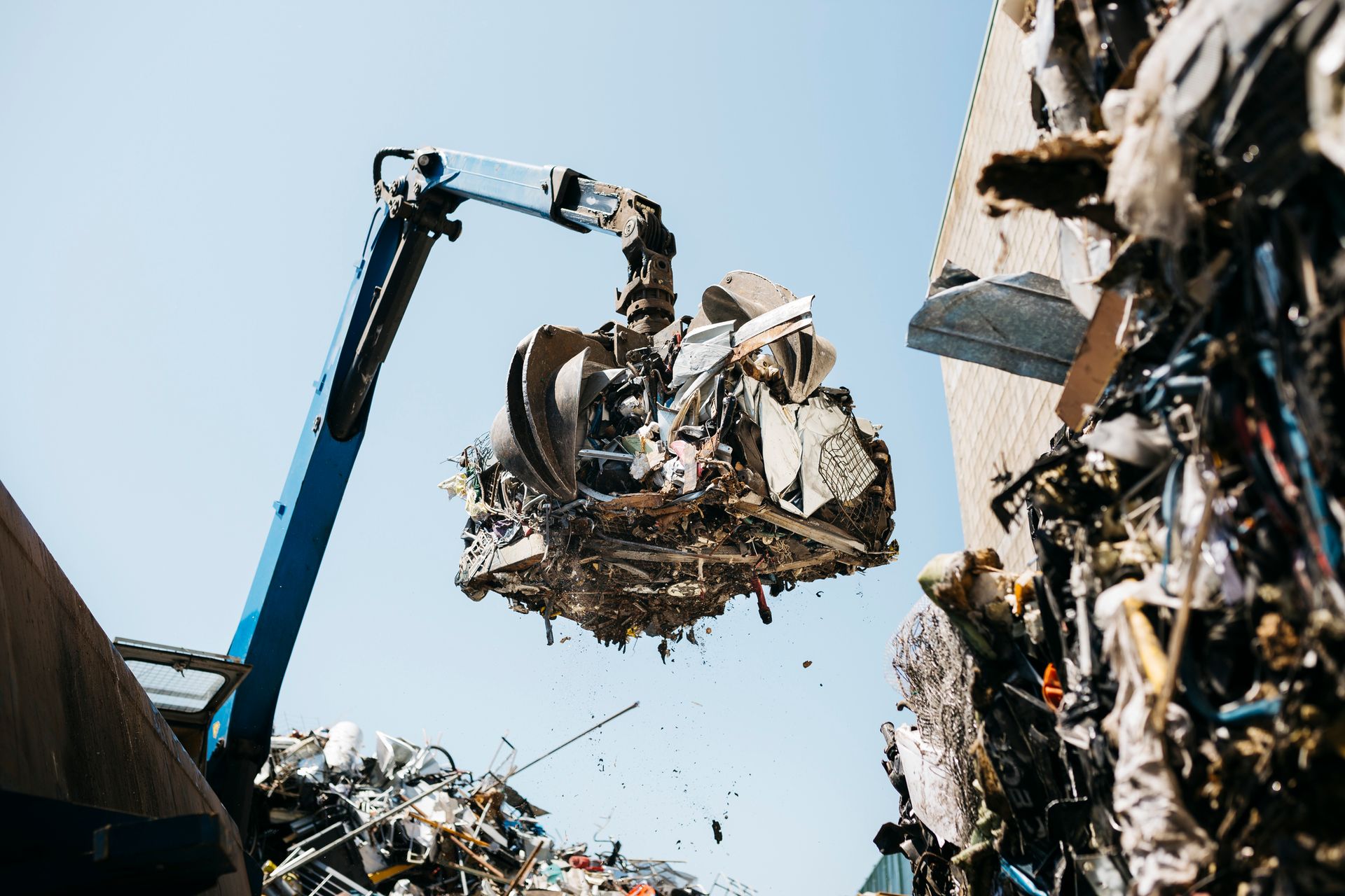 A crane elevates a large scrap metal pile at a metal recycling center.