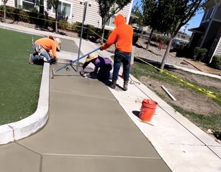 A group of people are working on a sidewalk.