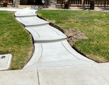 A concrete walkway going through a lush green lawn