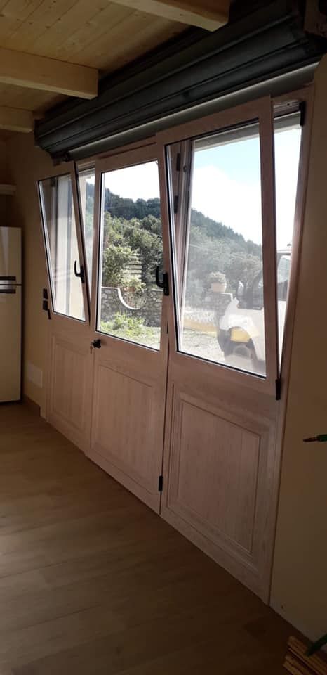Vista interna di una stanza con porte bianche e una finestra che si affaccia su una montagna. La stanza ha pavimenti in legno.