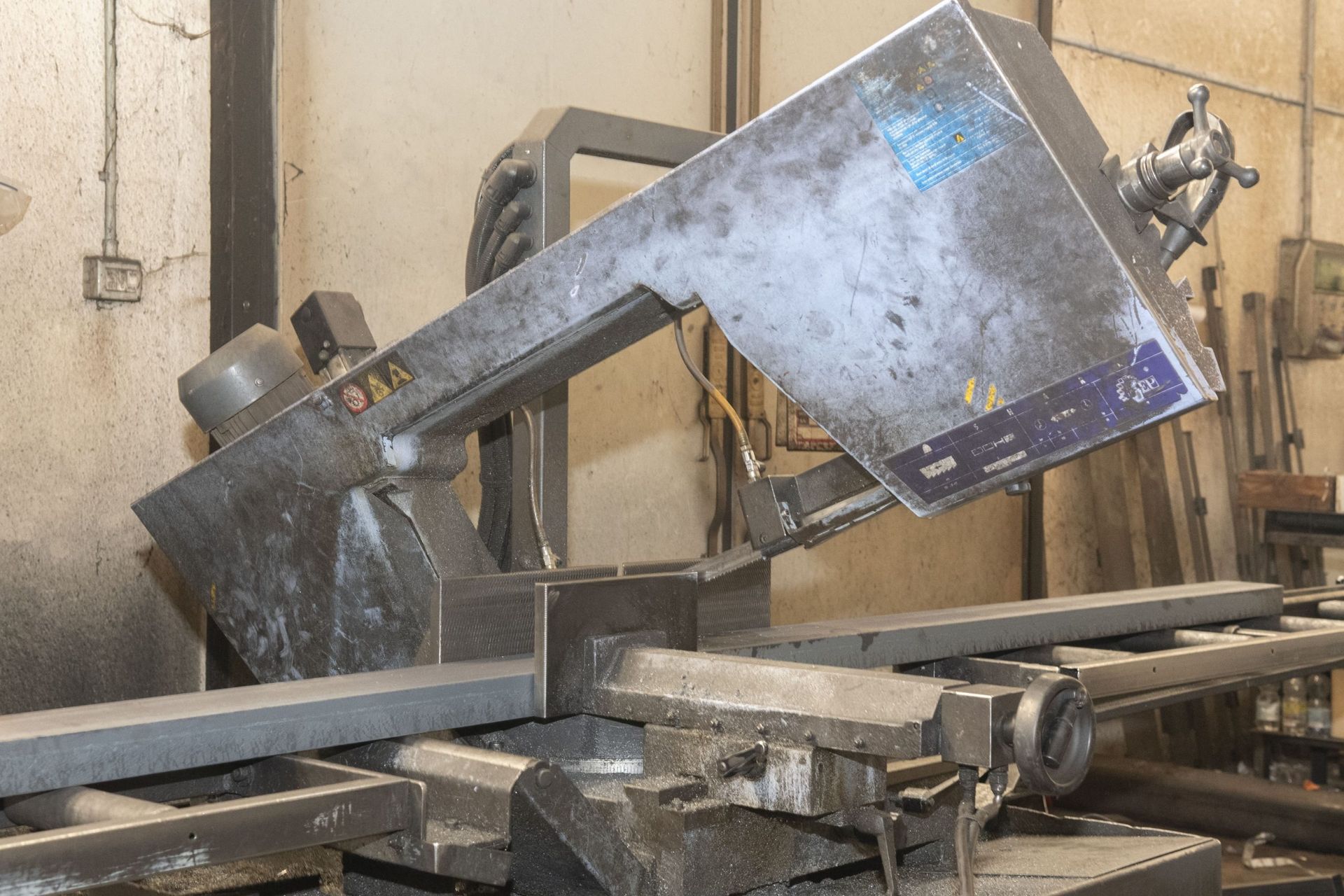 Una sega a nastro orizzontale che taglia una trave d'acciaio in un'officina.