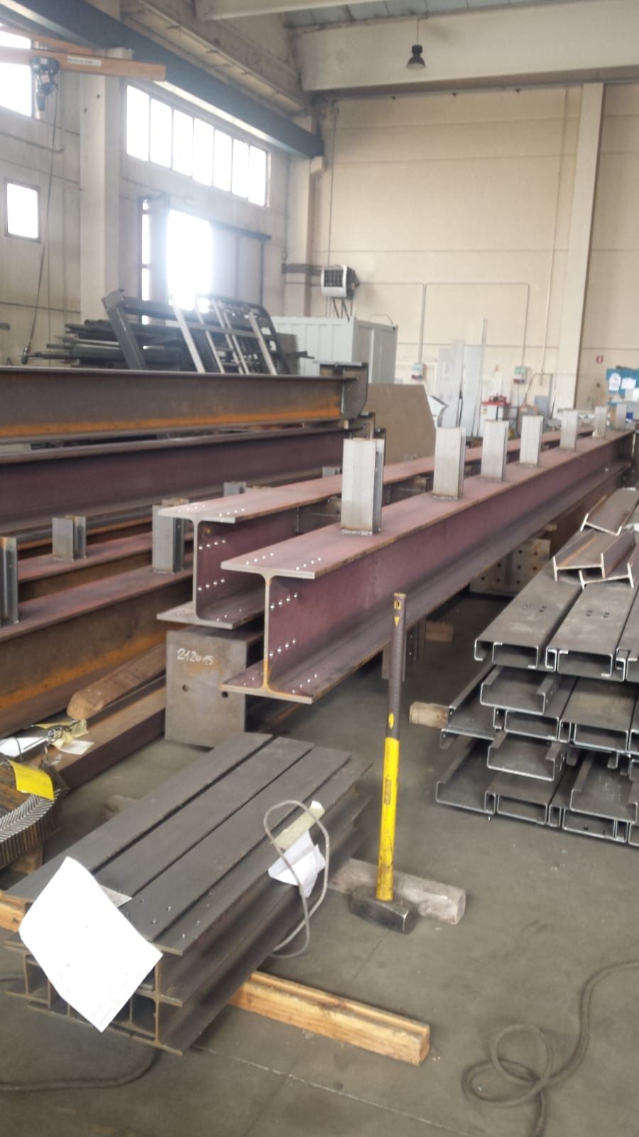 Travi a I in acciaio con piastre metalliche saldate, disposte in un'officina di fabbricazione industriale.