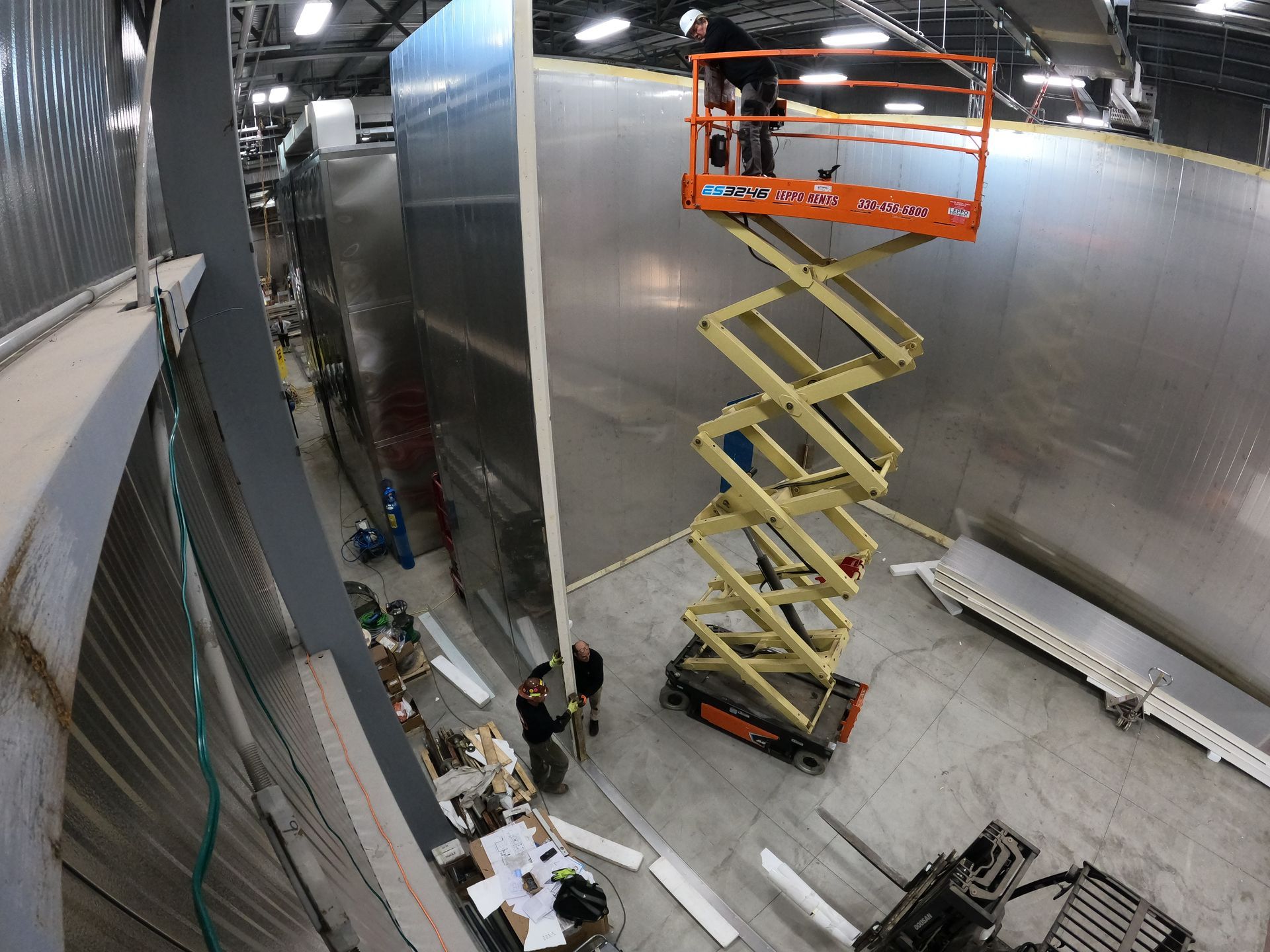 A man is standing on a scissor lift in a room.