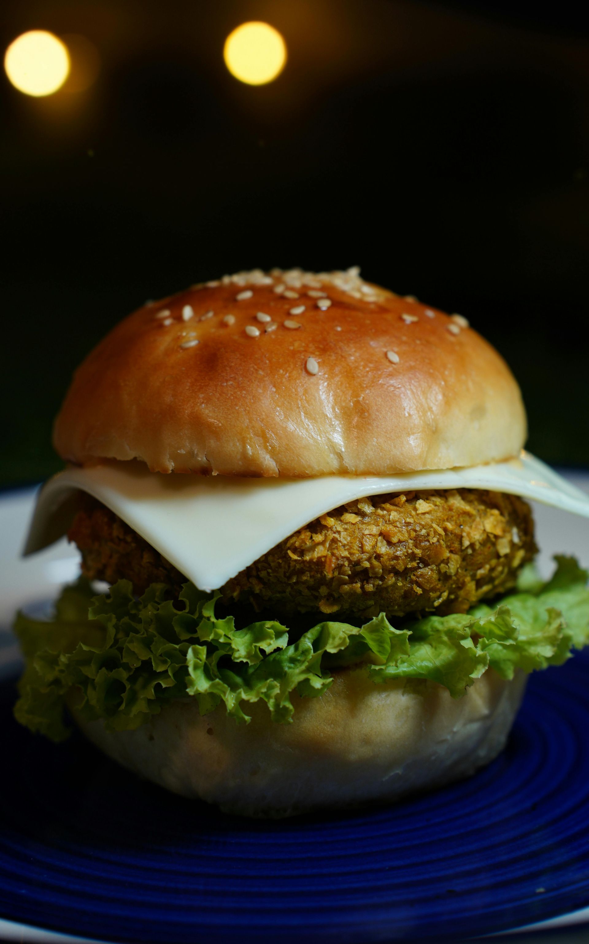 A close up of a hamburger on a blue plate.