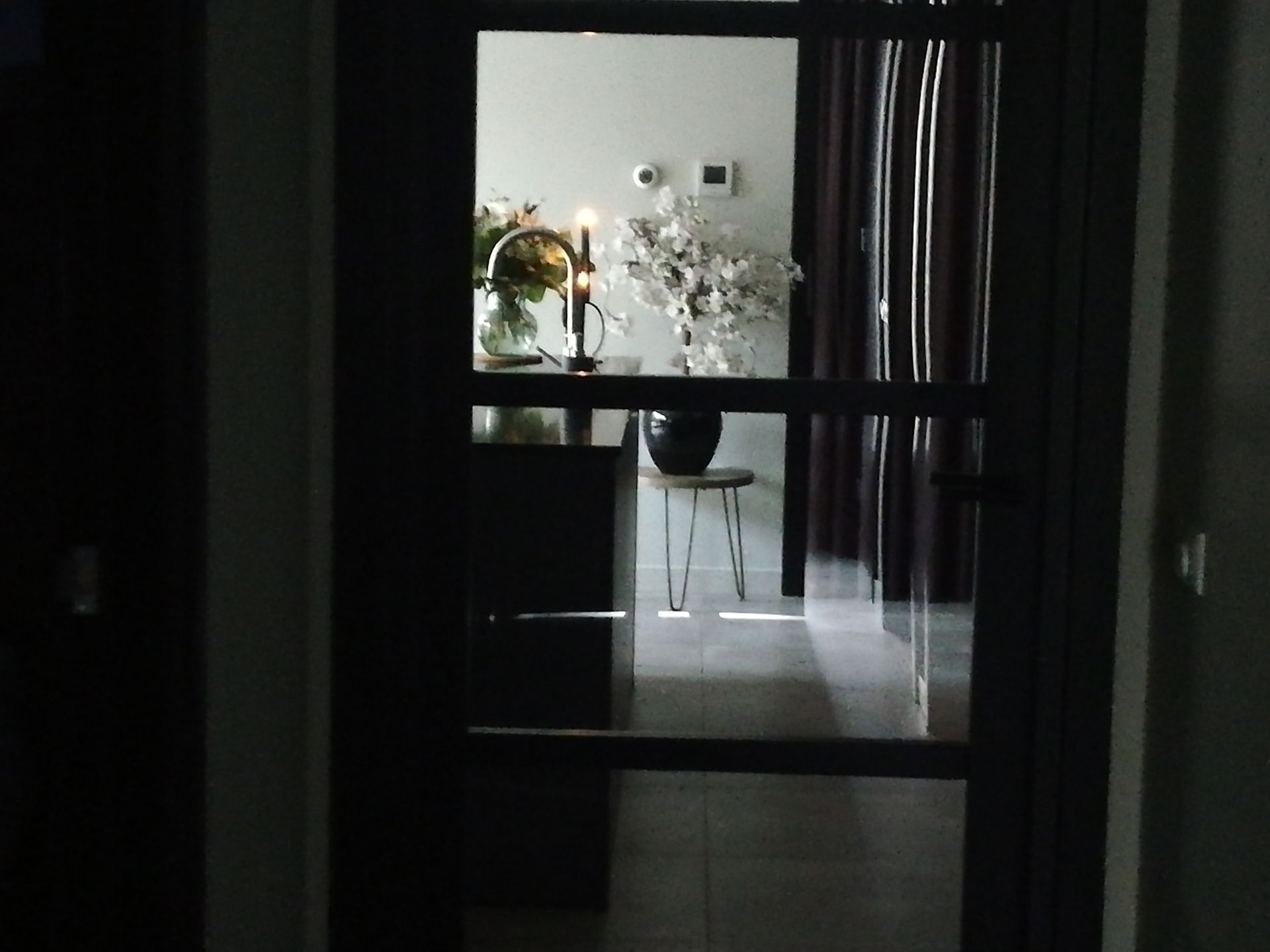 Een glazen binnendeur geeft toegang tot een kamer met kaarsen, bloemen 
