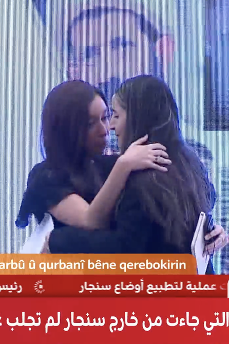 Lynn Zovighian embracing Yazidi Genocide survivor on stage during commemoration event.