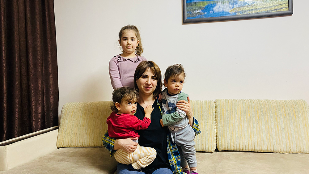Mariam Abrahamyan with her 3 kids sitting on a sofa in her house, in Nagorno-Karabagh