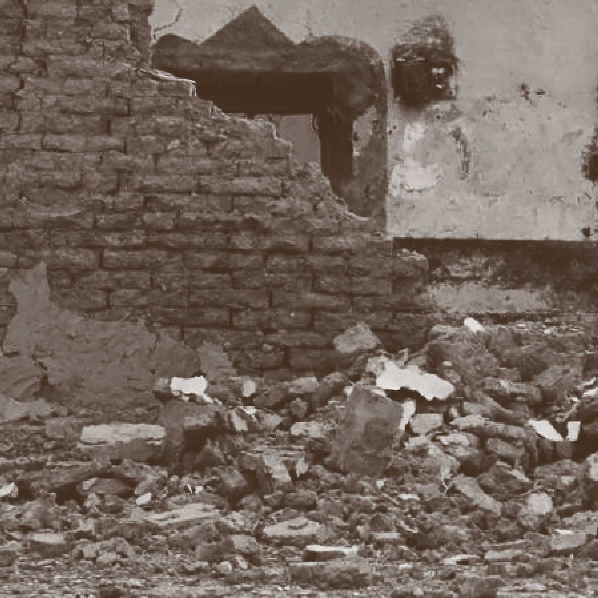 Ruined brick building with debris. Fragments of walls and a visible doorway frame.