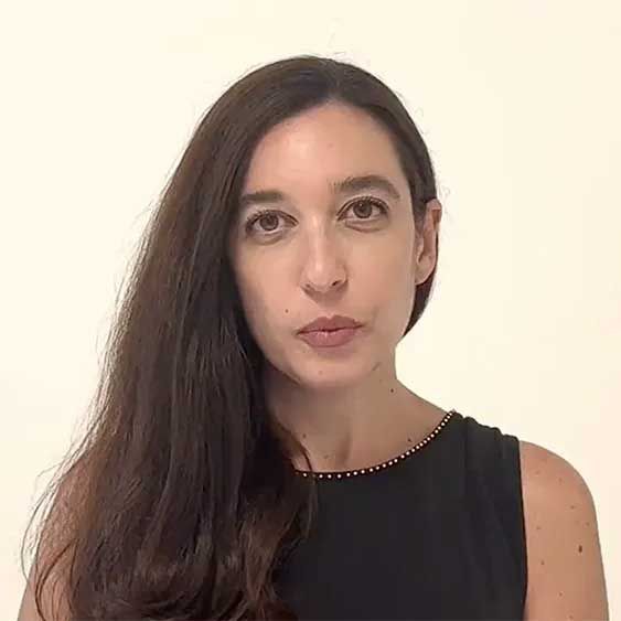 Lynn Zovighian with long brown hair, wearing a black top, looking directly at the viewer.