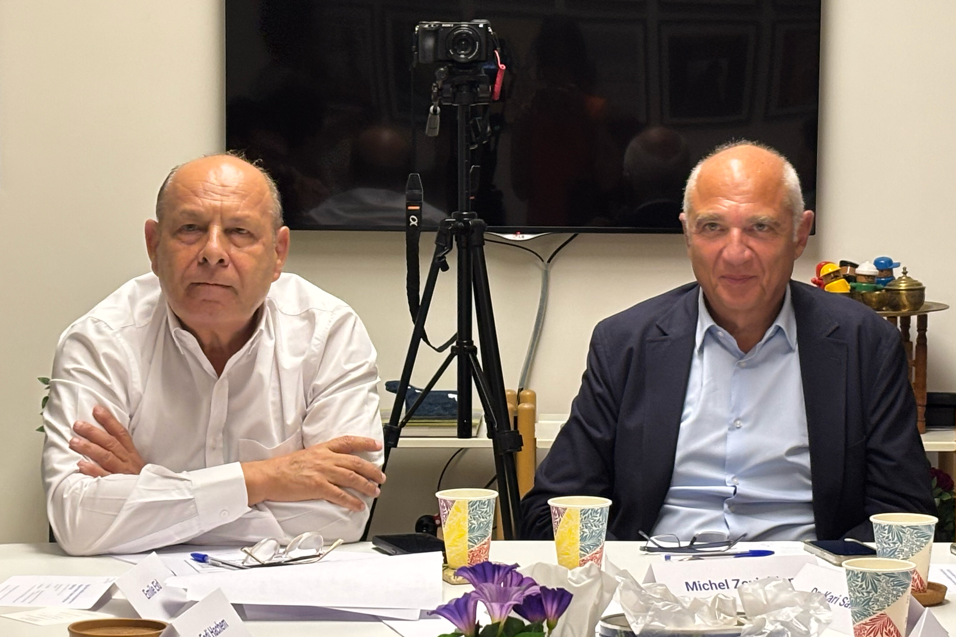 Habib Ephram & Michel Zovighian sitting at a table. One in a white shirt, the other in a blazer. Camera is behind them.