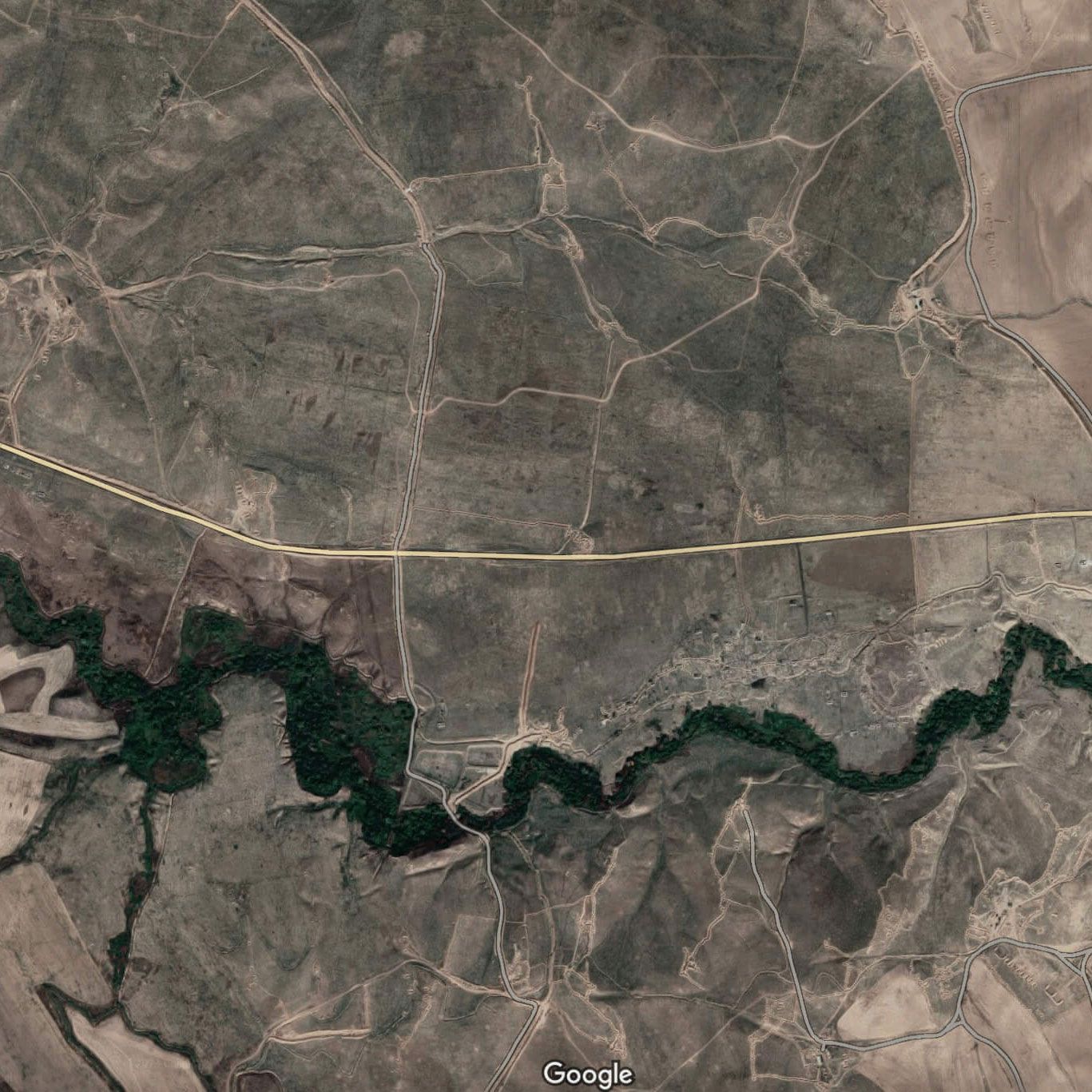 Aerial view of a dry, hilly landscape with a winding river and dirt roads. Lachin corridor visible.