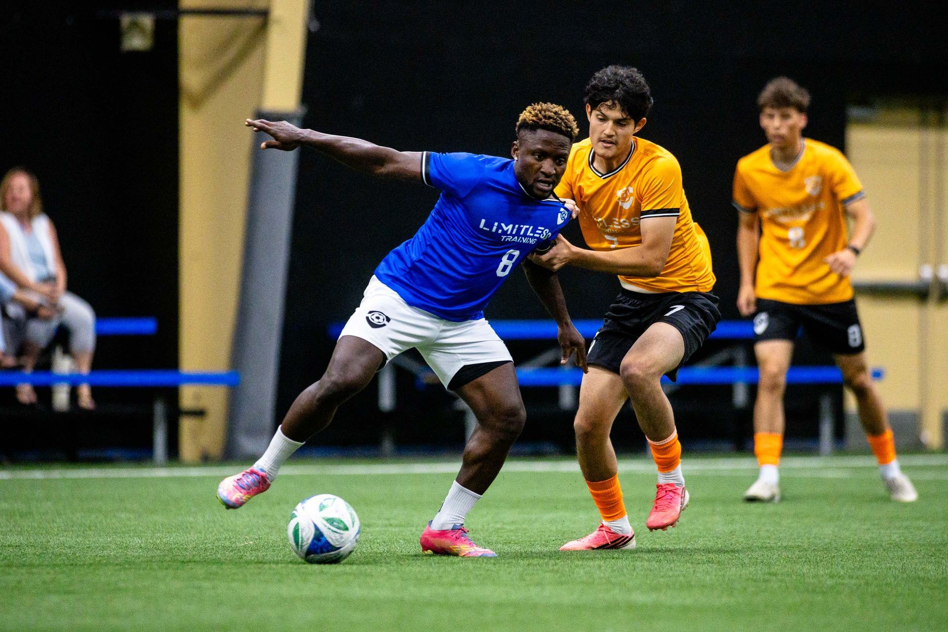 A player from Team Blue fights off the grabbing player from Team Yellow while defending the ball at the Viktoria Soccer Club indoor field.