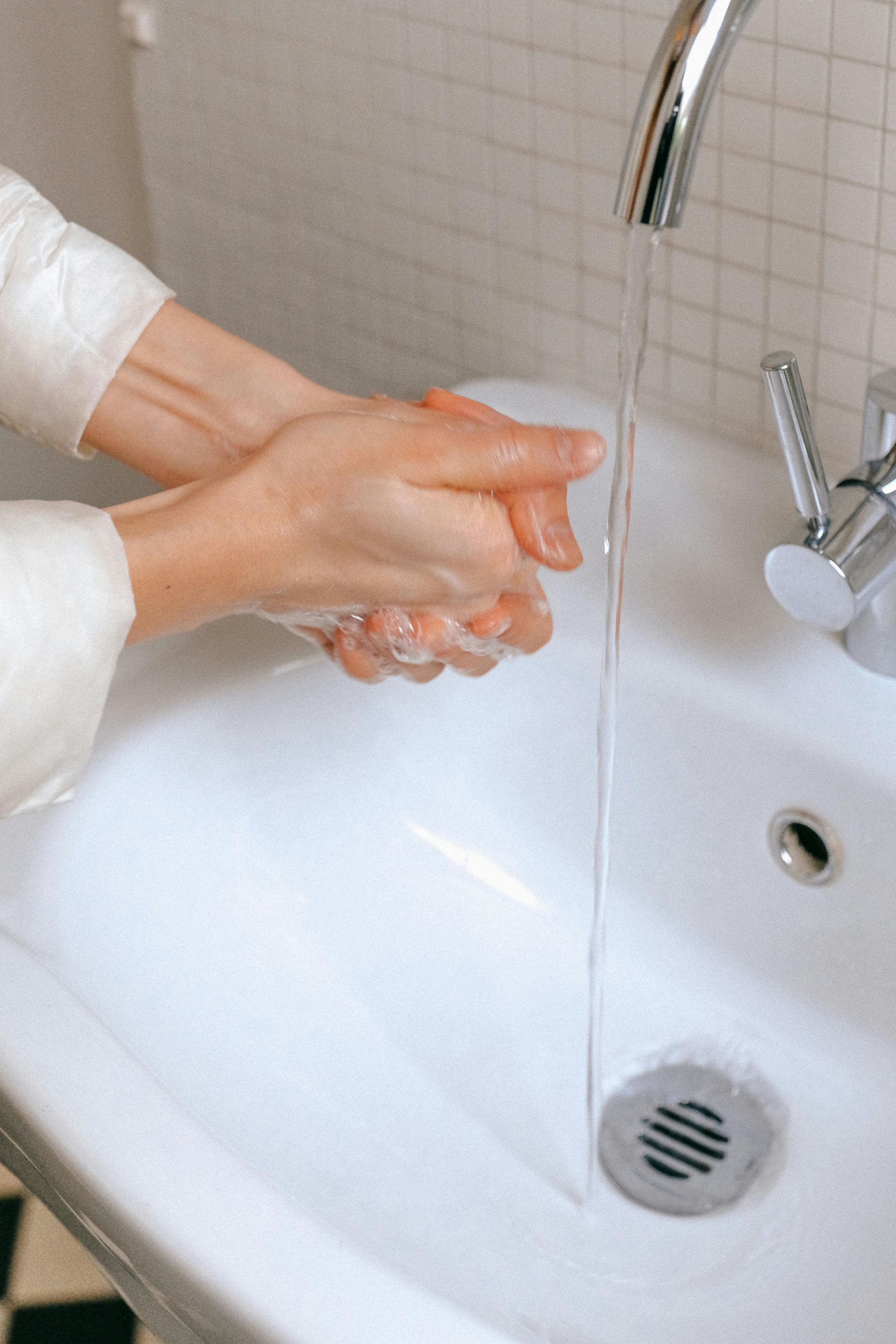 Person washing their hands in a bathroom sink