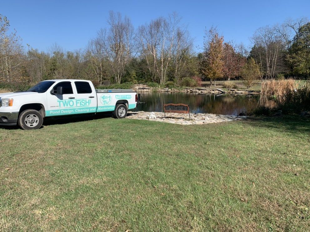 A man is standing next to a pond in a backyard.