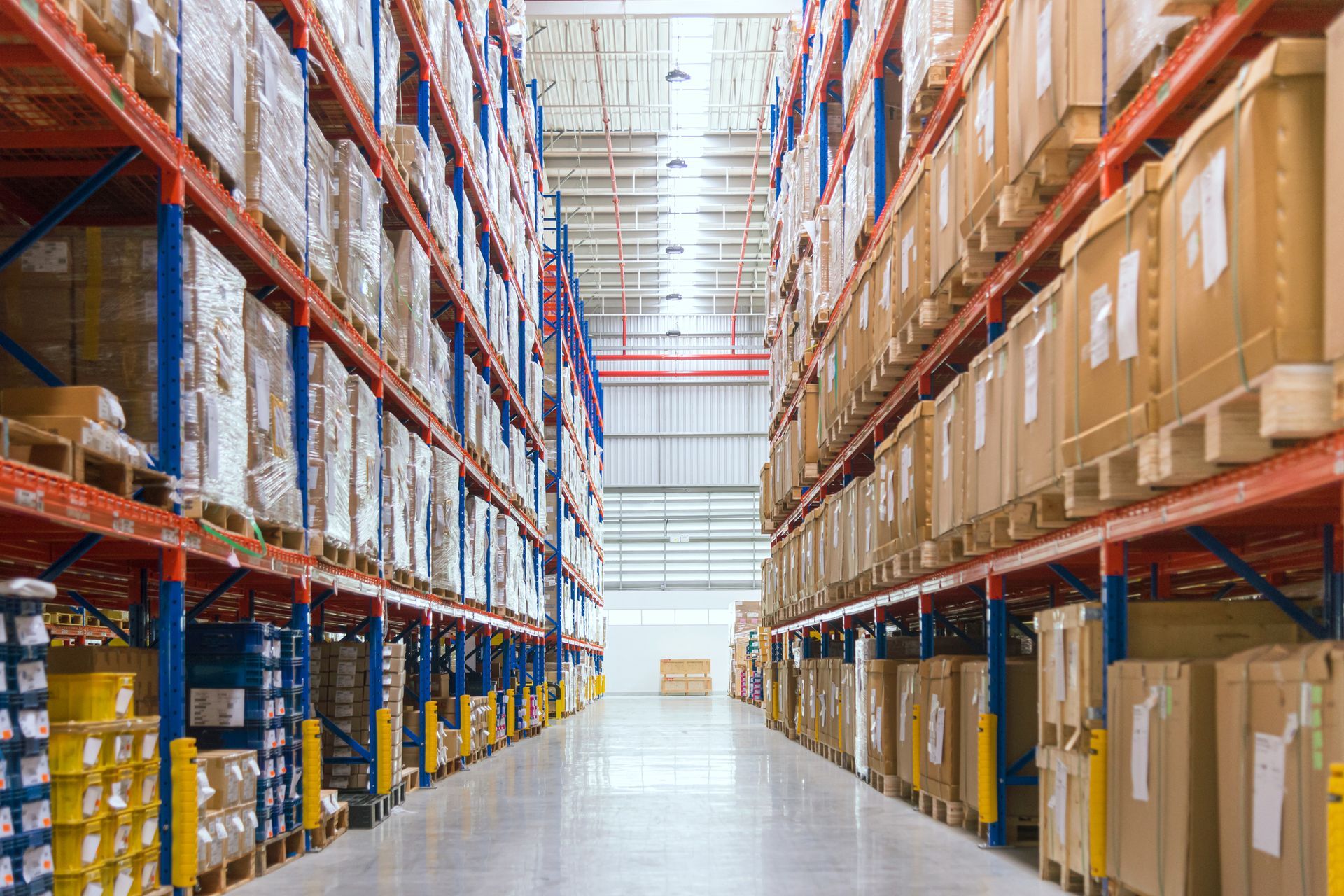 Rows of stacked boxes on shelves in a large, well-lit warehouse.