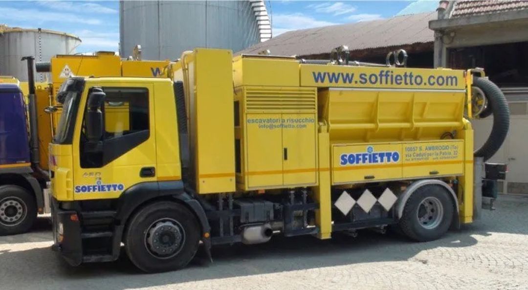 Un camion aspiratore industriale Soffietto di colore giallo brillante parcheggiato in un parcheggio all'aperto in una giornata di sole.