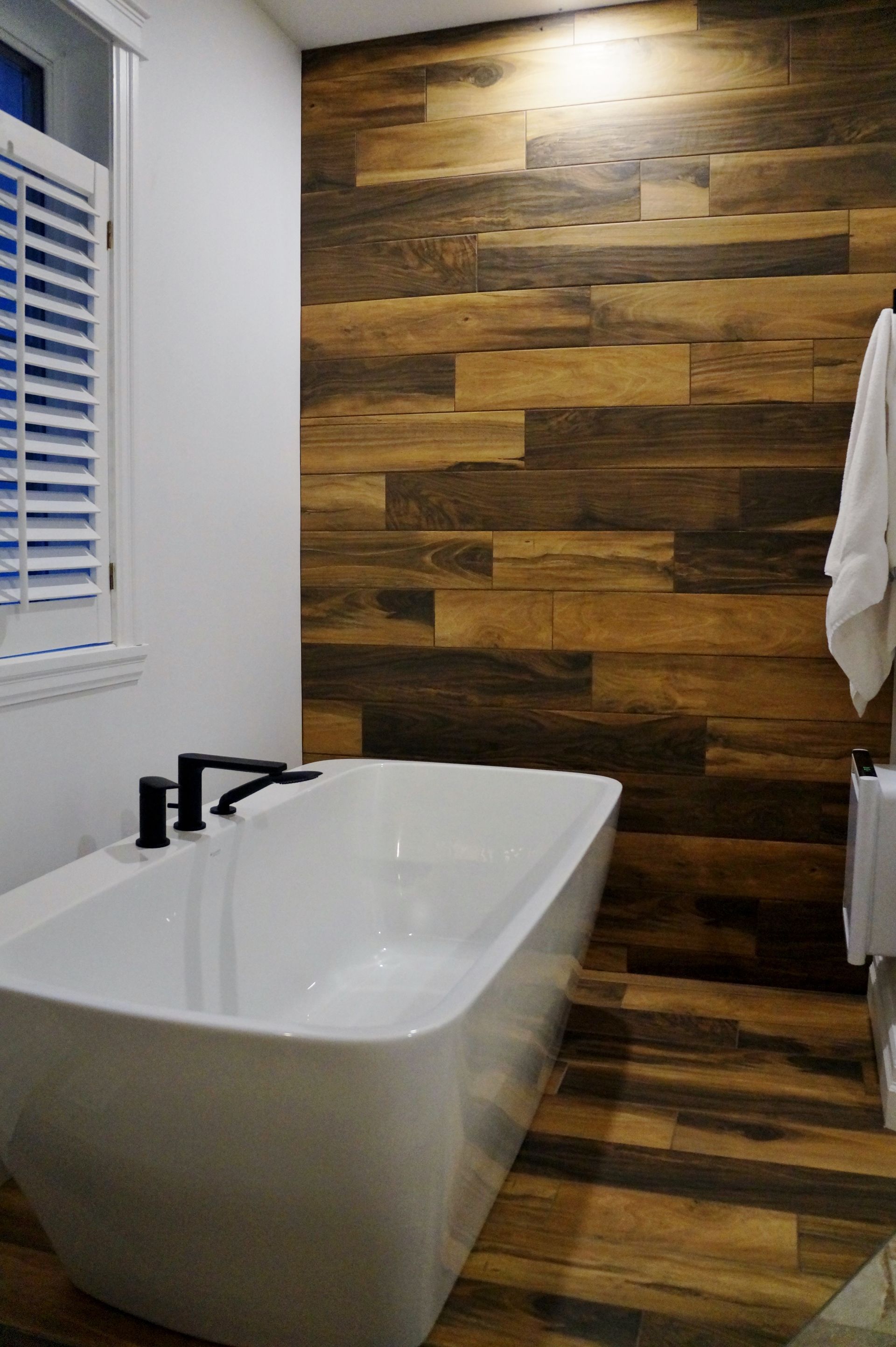 Une salle de bain avec baignoire et un mur en bois.